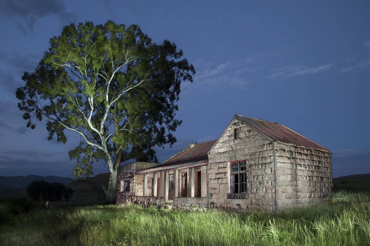 Gammelt forladt hus malet med lys om natten